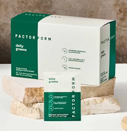 Factor Form branded box with daily greens powder packet in front, on aesthetic marble slab