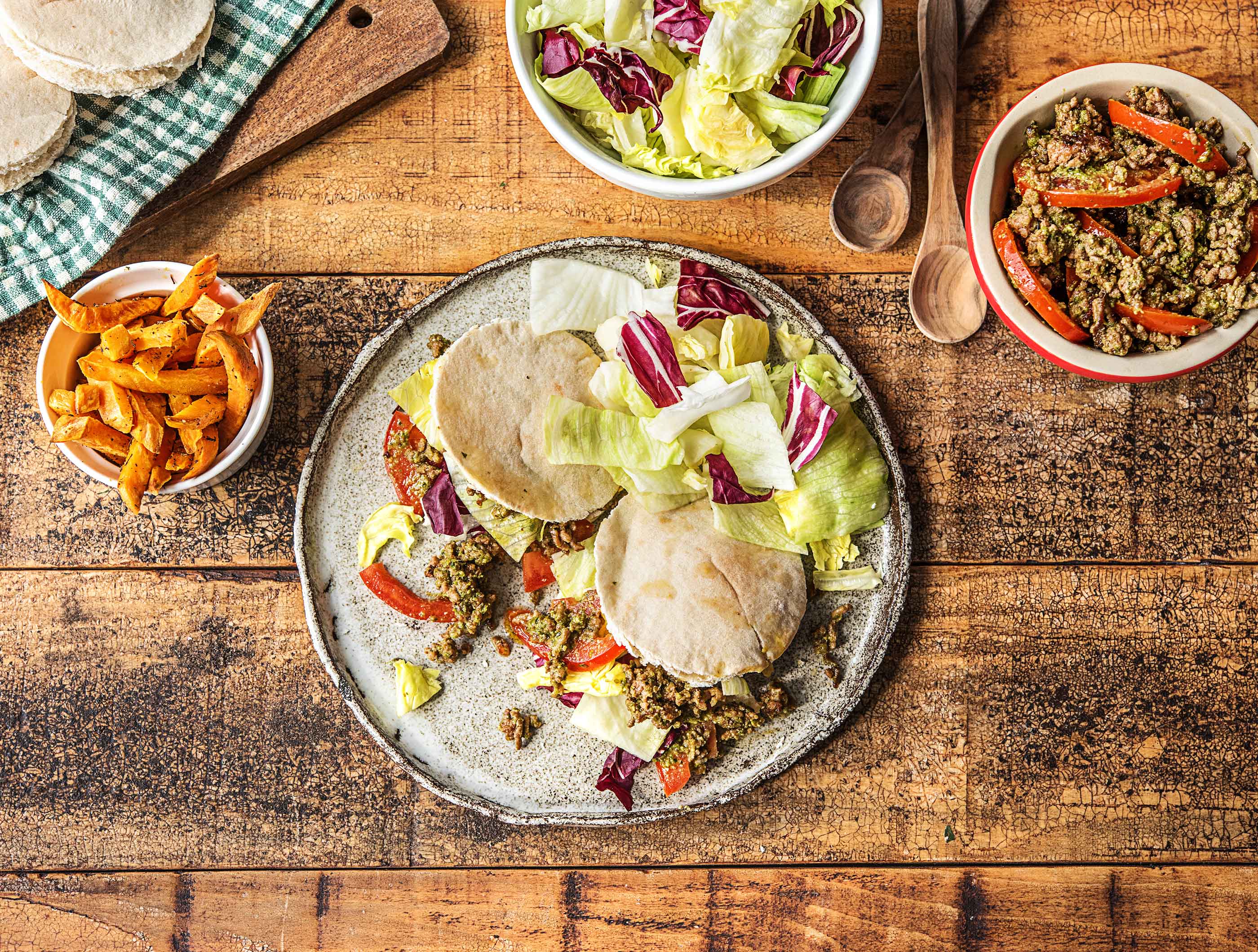 Italiaanse pitabroodjes met gehakt, tomaat-pestosalade, bataat en knapperige ijsbergsla