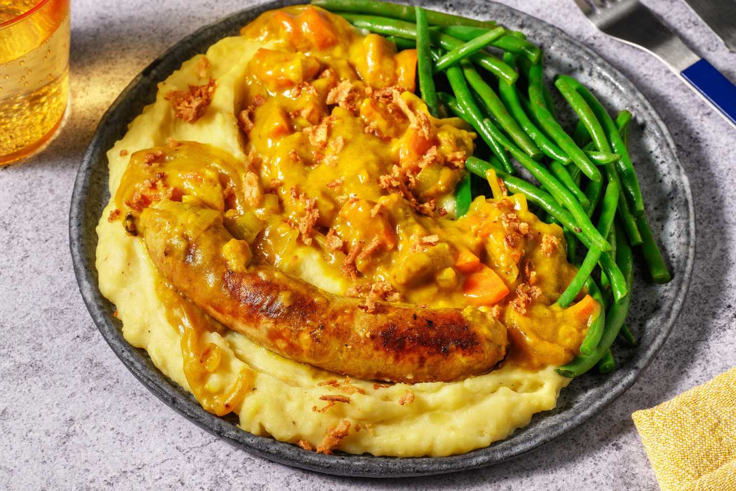Saucisse de porc en sauce au curry et oignons frits