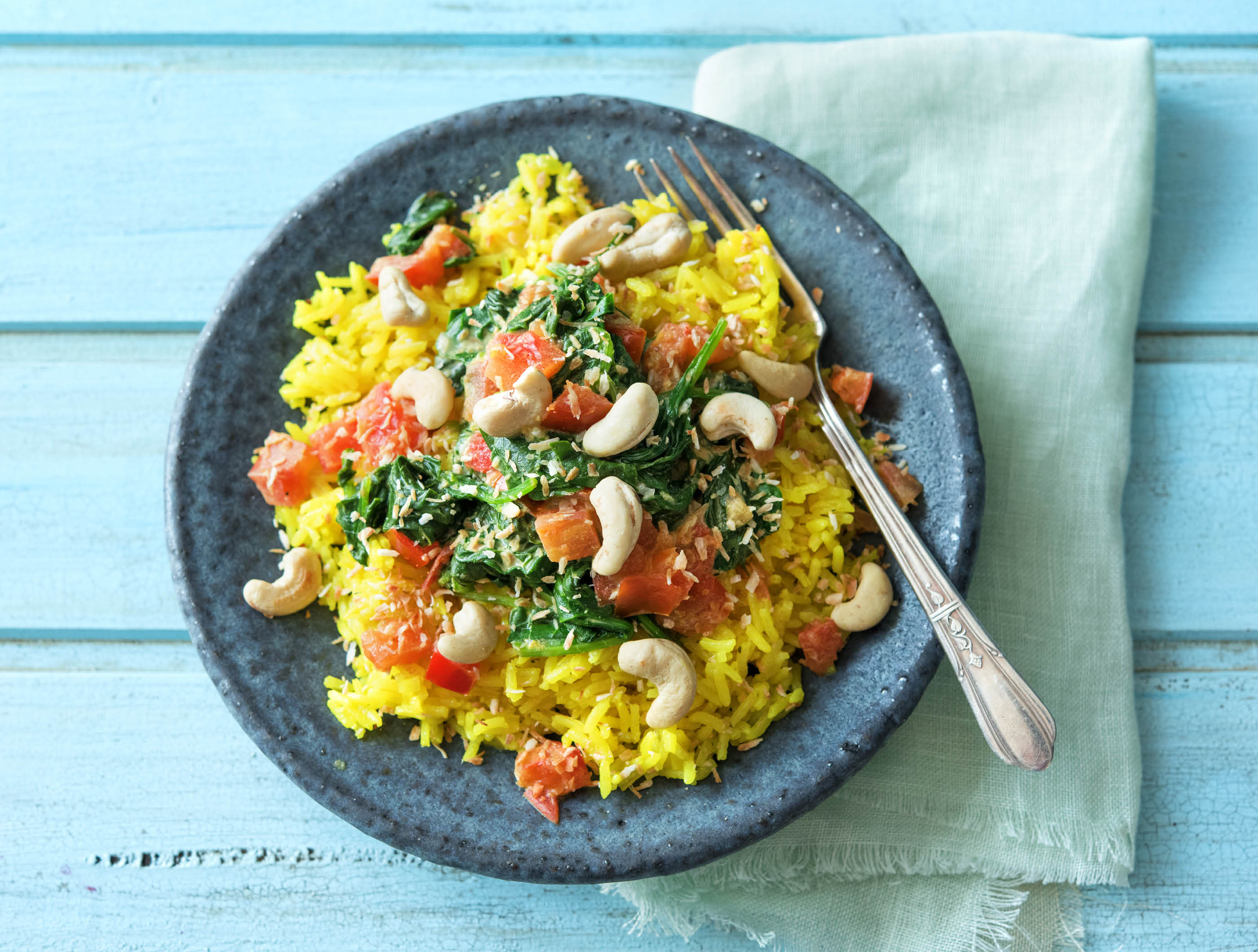 Gele rijst met curry van spinazie, tomaat en cashewnoten