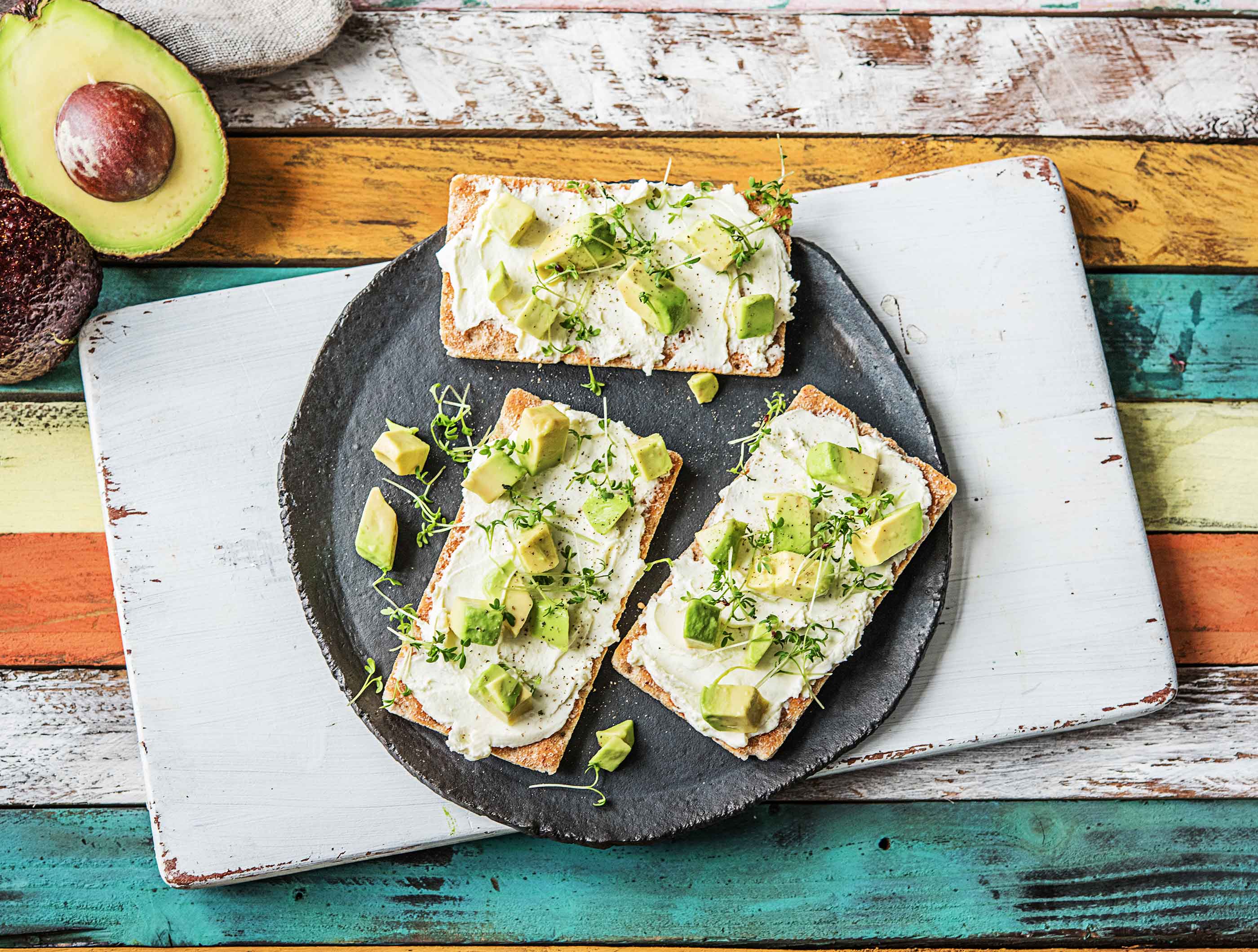 Vezelrijke crackers met verse geitenkaas, avocado en alfalfa