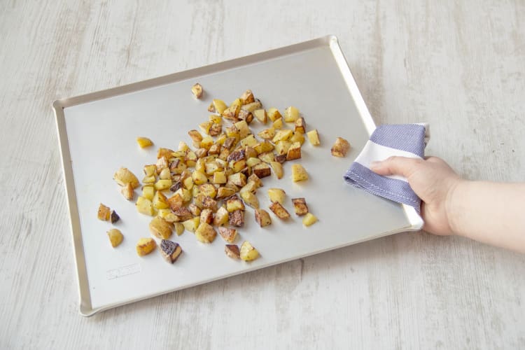 Cut, season, and toss the potatoes on a baking sheet