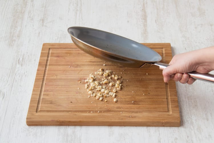 Bash hazelnuts into small pieces with base of pan