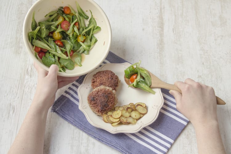 Verdeel de hamburgertjes en aardappelen over de borden en serveer met de tomatensalade