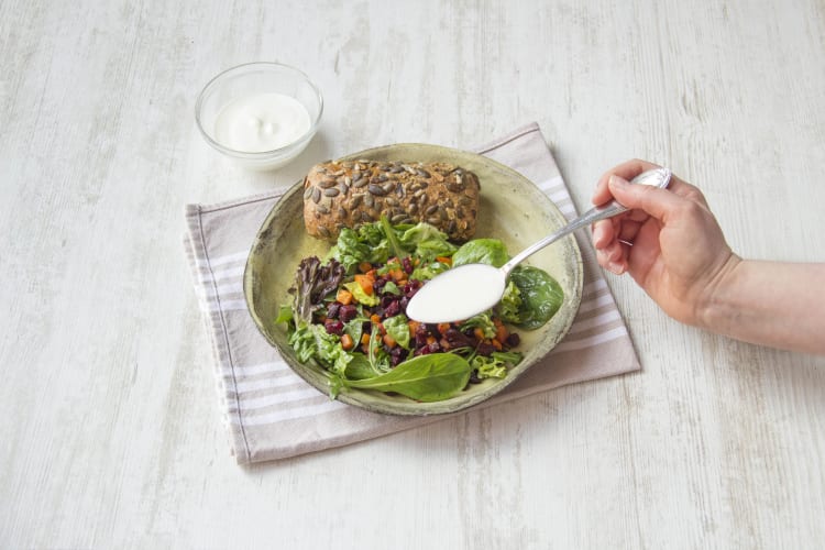 Verdeel de salade over de borden en schep de yoghurt over de salade