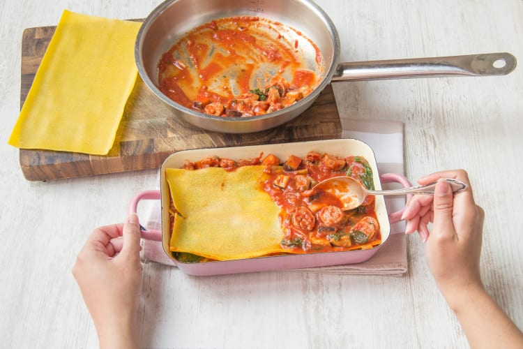 Vul de saus en de lasagnebladen in laagjes in de ovenschaal