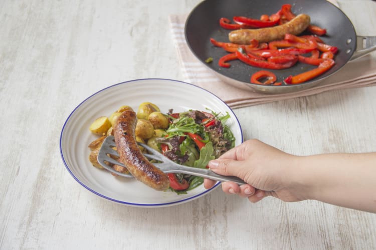 Verdeel de worst en krieltjes over de borden en serveer met de salade.