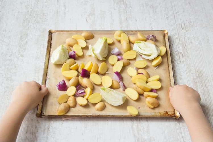 Kartoffeln und Gemüse auf dem Blech verteilen