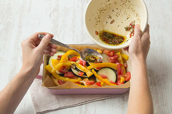 Giet de dressing over de groenten in de ovenschaal.