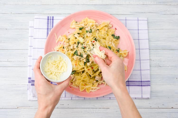 Verdeel de pasta over de borden en garneer met kaas.