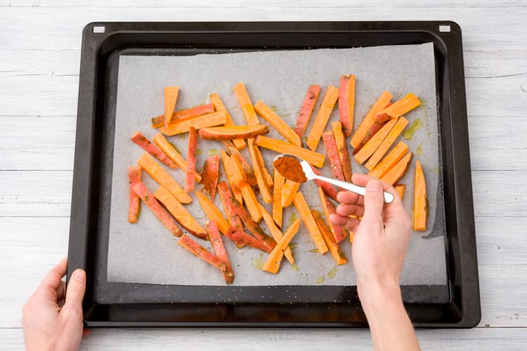 erdeel de frietjes over een bakplaat met bakpapier.