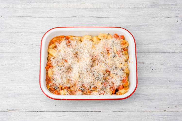Giet de gnocchi met saus in een ovenschaal en bestrooi met pecorino.