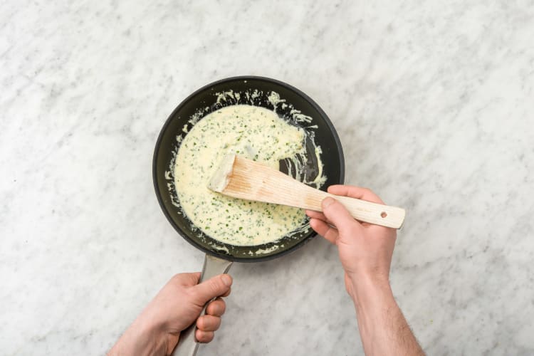 Roer de crème fraîche en bieslook door het bakvet van de vis.
