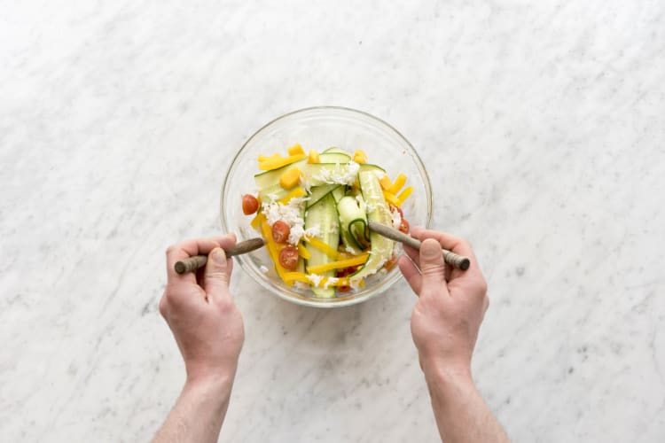 Meng alle ingrediënten in de saladekom.