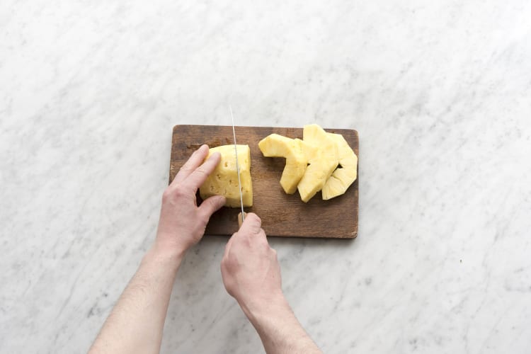 Snijd de ananas in halve plakken.