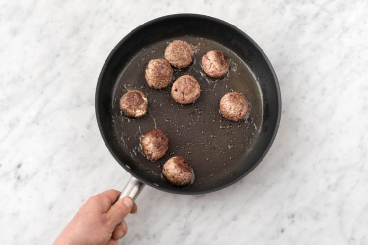 Boil the pasta and sear the meatballs