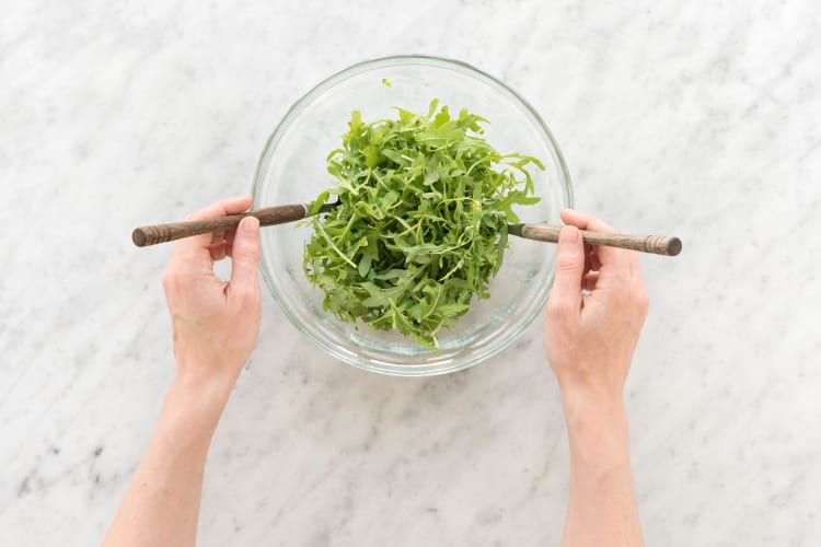 Rucola mit dem Dressing vermischen