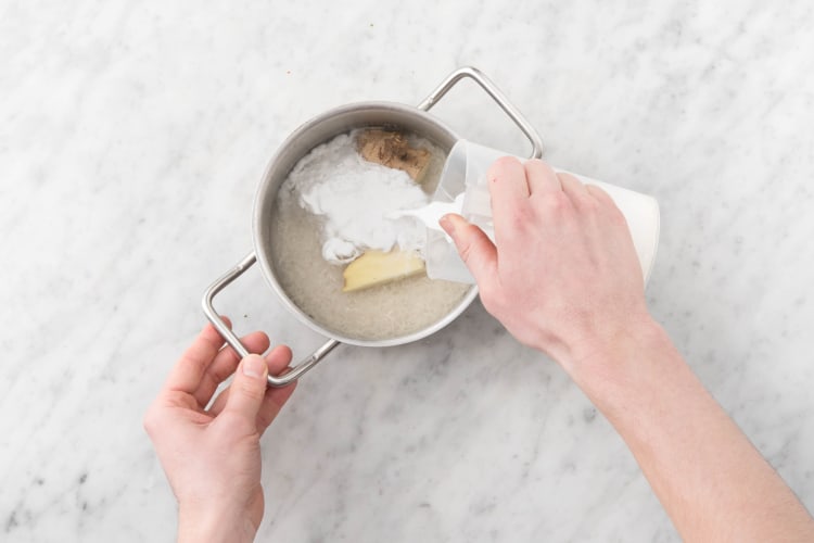 Ajouter à la casserole le gingembre, la moitié du lait de coco et le riz