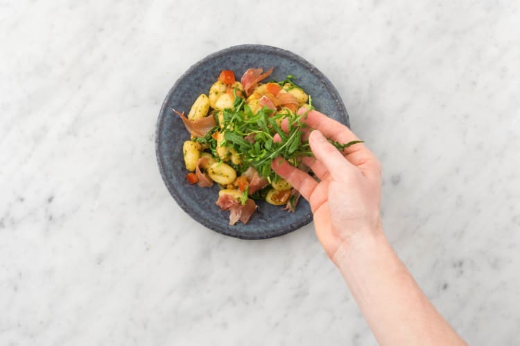 Verdeel de gnocchi over de borden en garneer met de serranoham en overige rucola