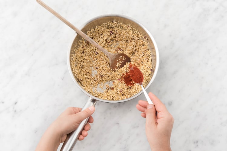 Voeg de quinoa, komijnpoeder en paprikapoeder toe.