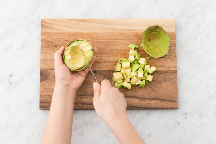 Snijd ondertussen de avocado doormidden, snijd het vruchtvlees in blokjes en lepel uit de schil.