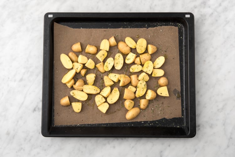 Disposer les grenailles, ainsi que le romarin, sur une plaque recouverte de papier de sulfurisé. Les recouvrir de la moitié de l’huile d’olive, puis saler et poivrer.