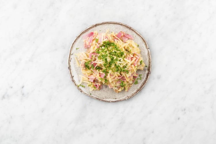 Servez la purée sur les assiettes et garnissez du reste de jambon et de vieux fromage ainsi que de persil.