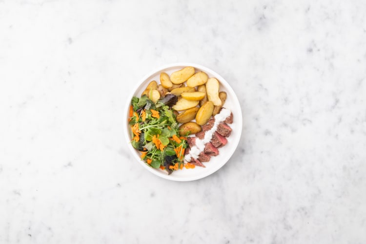 Su un bancone piastrellato nero vengono offerte porzioni di patatine fritte  con sopra formaggio e carne macinata di manzo t