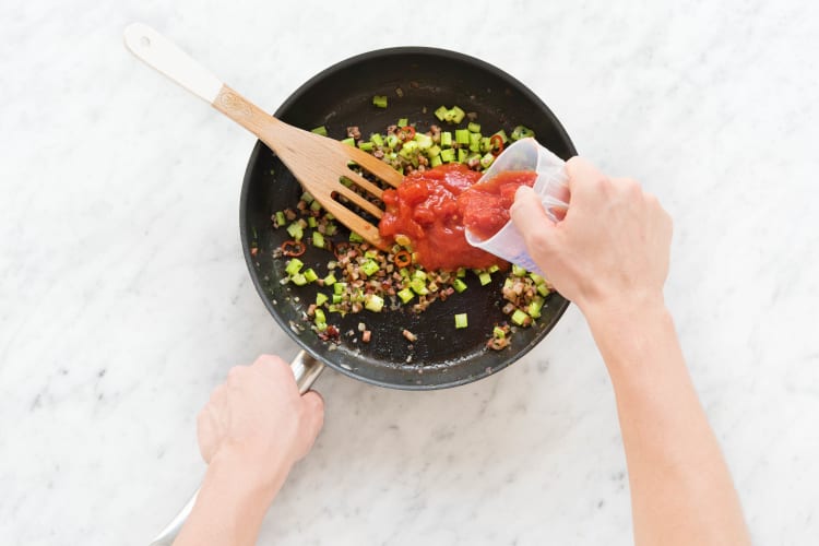 Mit stückigen Tomaten und Hühnerbrühe ablöschen