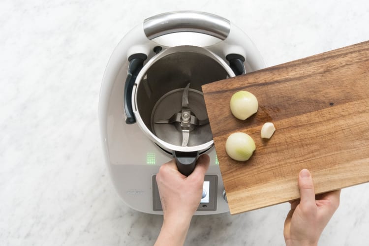 Zwiebelhälfte und Knoblauch in den Mixtopf geben