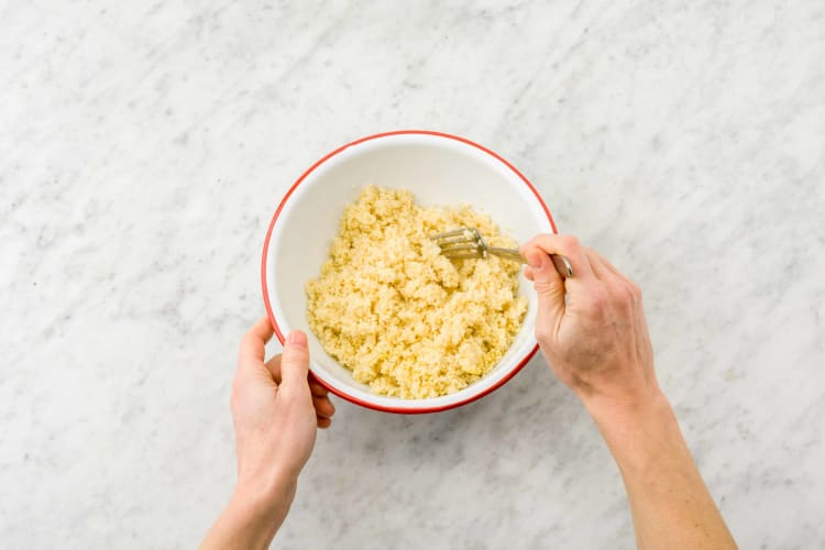 Meng de couscous met de bouillon in een saladekom.